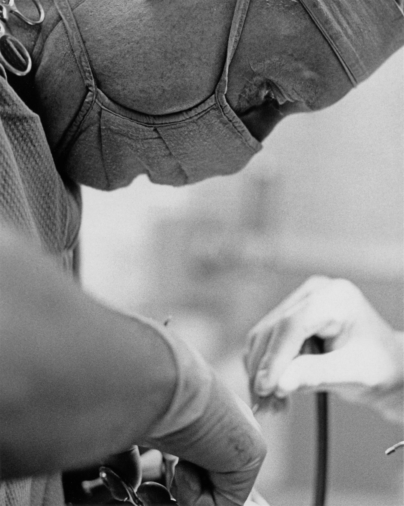 Surgeon in cap and mask working over an operating table